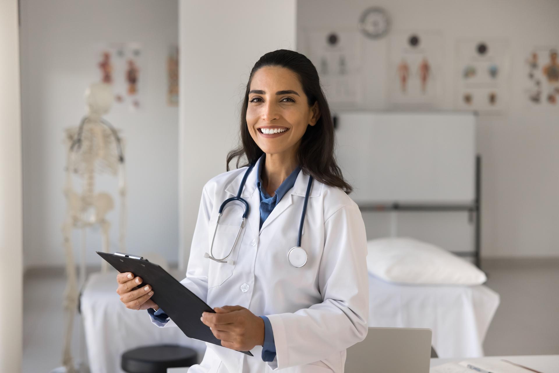 Beautiful Latina female cardiologist holding clipboard posing for camera